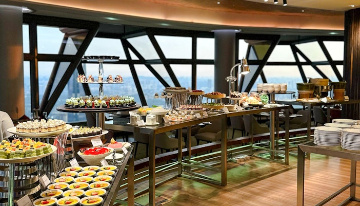 Lunch buffet spread at ORBIT Revolving Dining, KL Tower, featuring assorted desserts and city view.