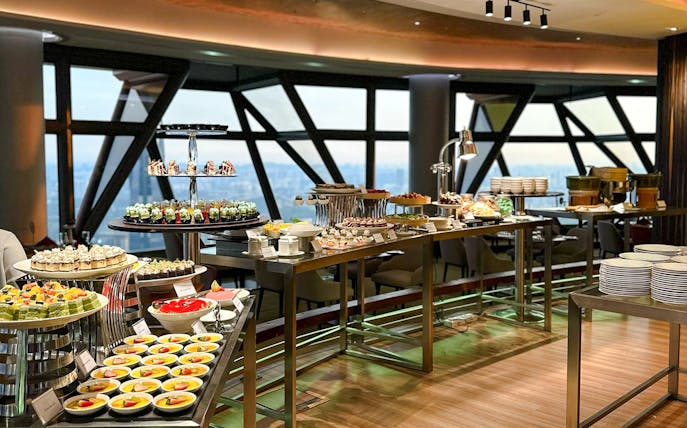 Lunch buffet spread at ORBIT Revolving Dining, KL Tower, featuring assorted desserts and city view.