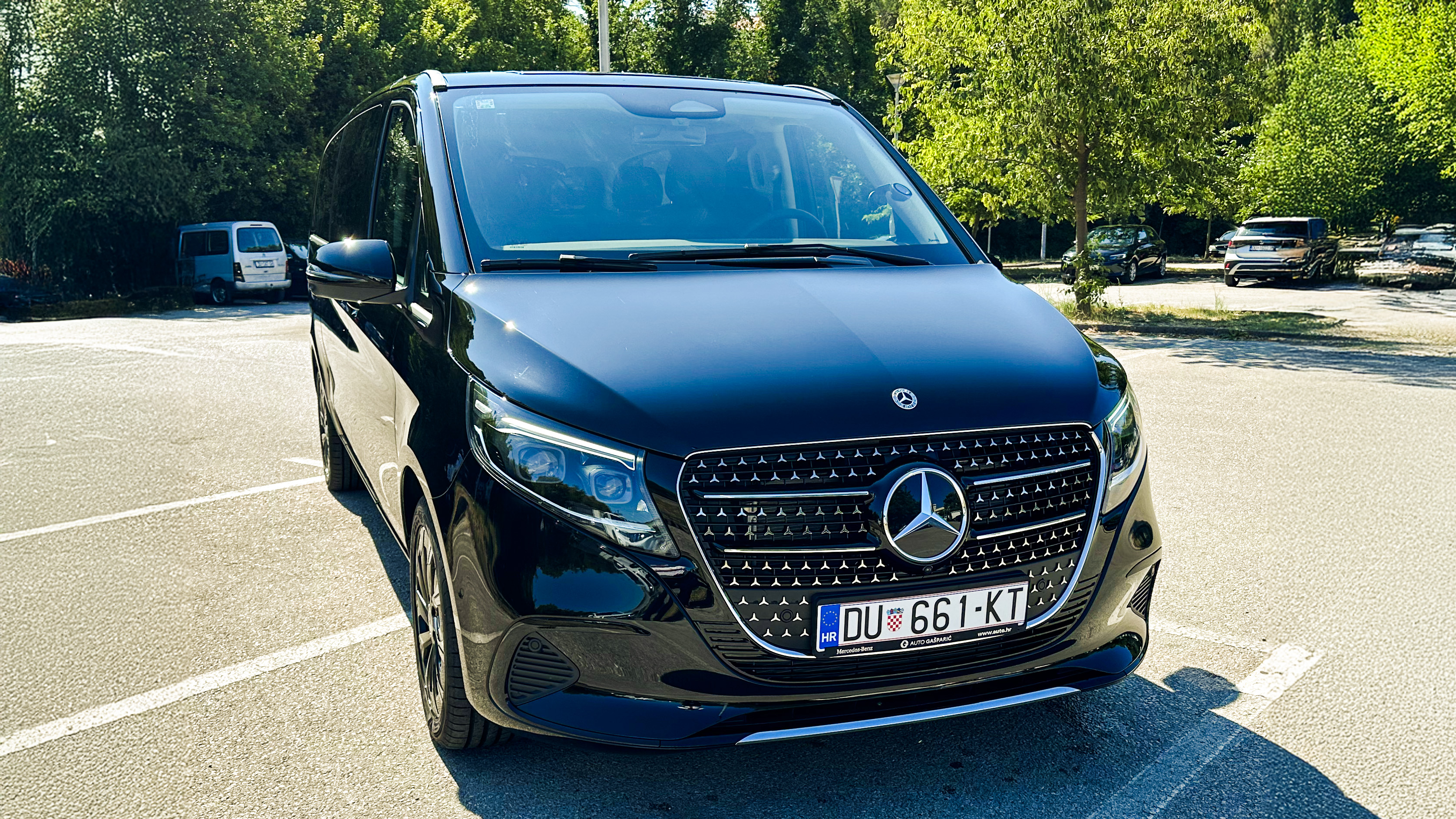 Black Mercedes-Benz transfer vehicle parked in a sunny lot.