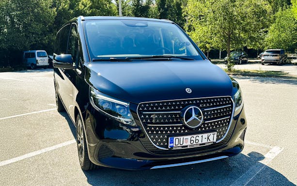 Black Mercedes-Benz transfer vehicle parked in a sunny lot.