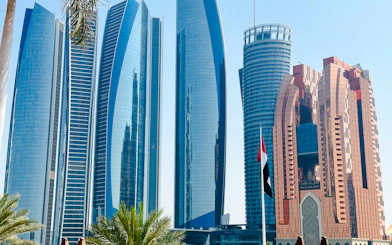 Skyscrapers of Etihad Towers and Bab Al Qasr Hotel in Abu Dhabi with UAE flag in foreground.