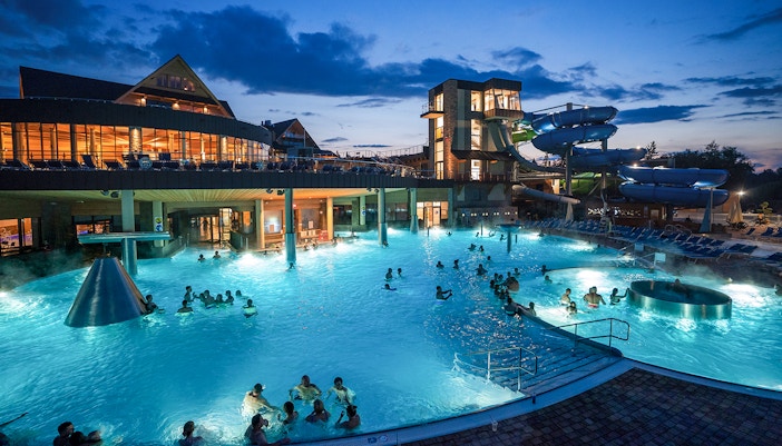 Tourists relaxing in Chochołow Thermal Baths with mountain view, transfers from Zakopane included.