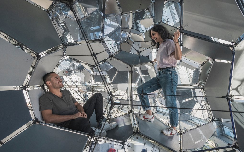 Visitors exploring geometric structure inside Glories Skyline Tower, Barcelona.