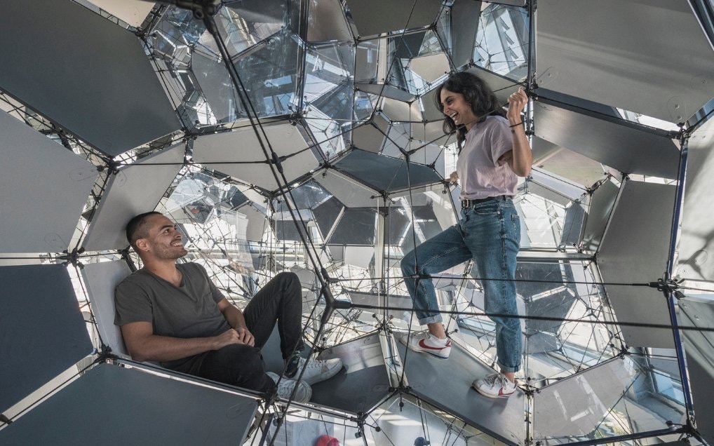 Visitors exploring geometric structure inside Glories Skyline Tower, Barcelona.
