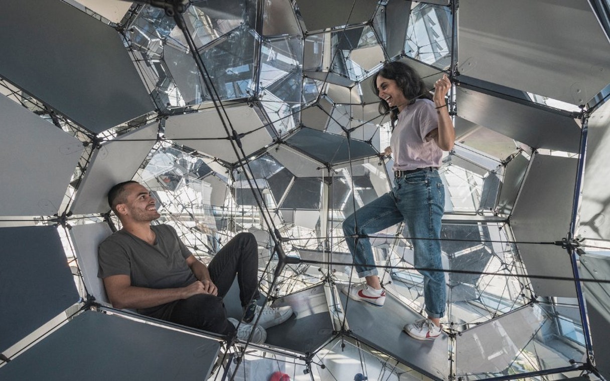 Visitors exploring geometric structure inside Glories Skyline Tower, Barcelona.
