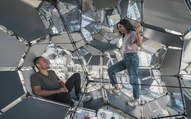 Visitors exploring geometric structure inside Glories Skyline Tower, Barcelona.