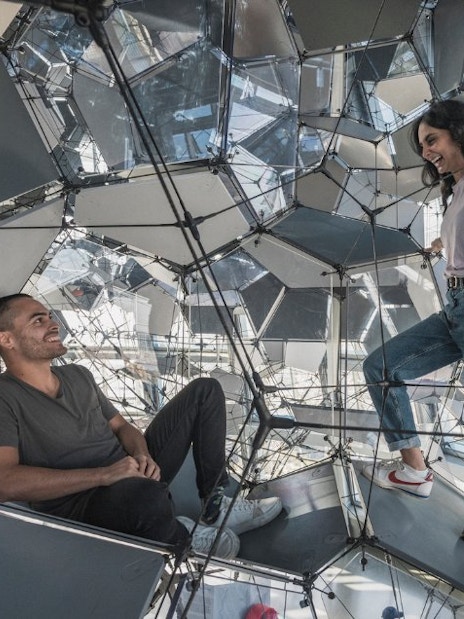 Visitors exploring geometric structure inside Glories Skyline Tower, Barcelona.