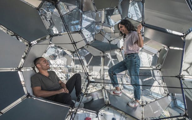 Visitors exploring geometric structure inside Glories Skyline Tower, Barcelona.