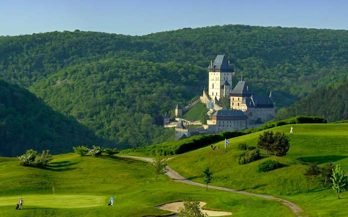 Karlstejn Castle surrounded by lush green hills in the Czech Republic.
