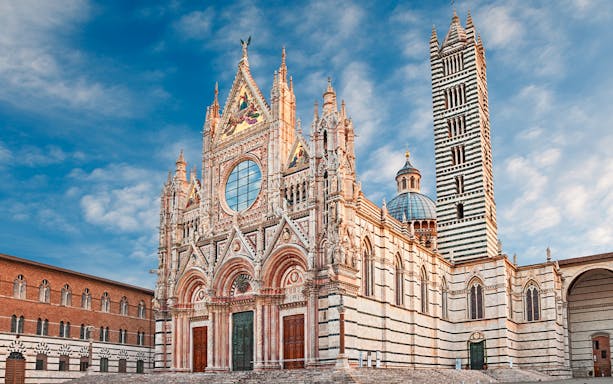 Siena Duomo facade with intricate Gothic architecture under a blue sky.