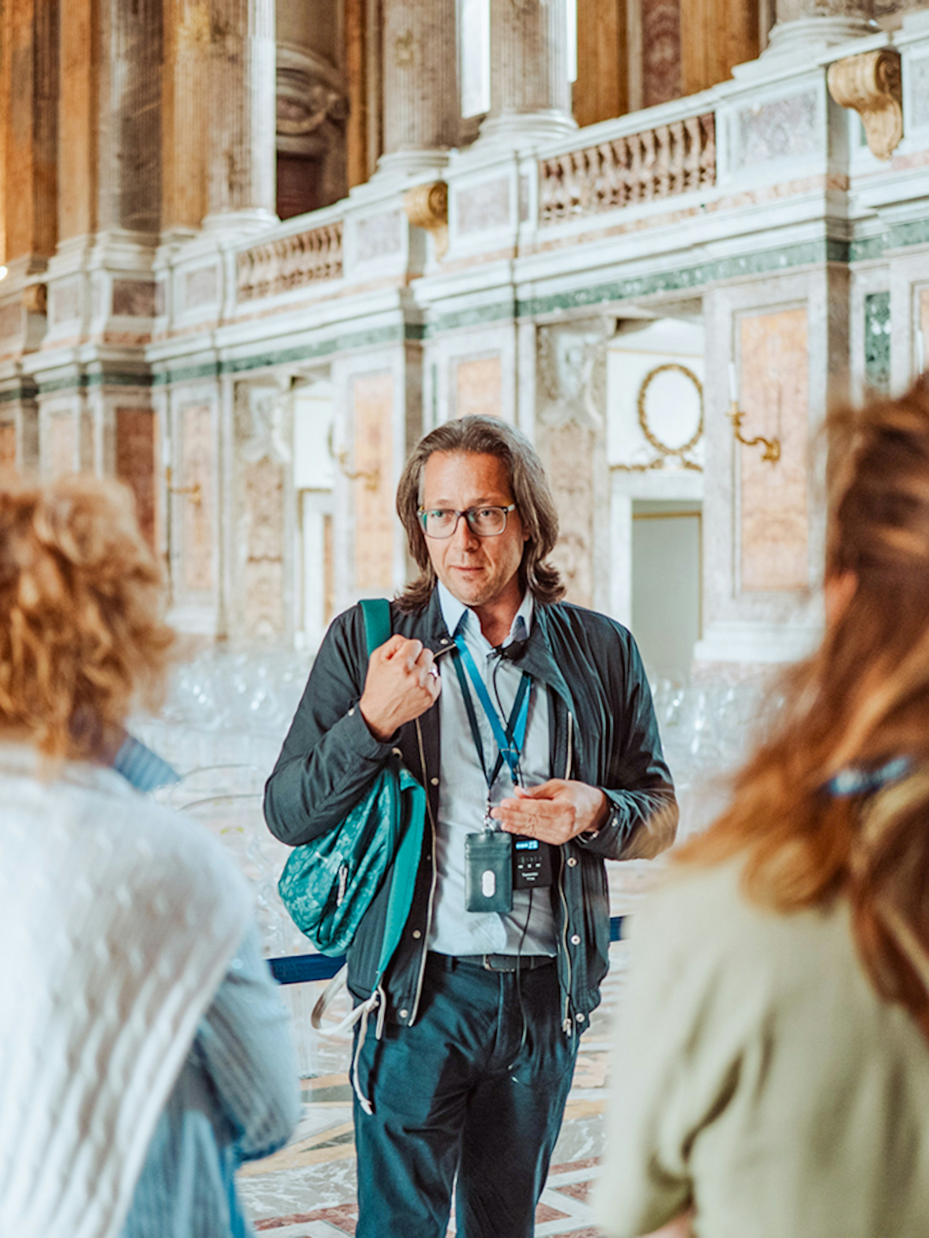 Tour guide leading a group inside the Royal Palace of Caserta, Italy.