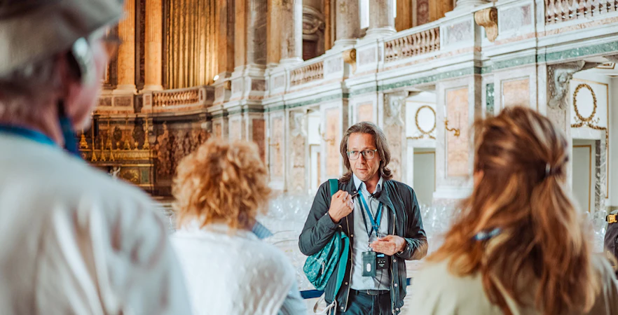 Tour guide leading a group inside the Royal Palace of Caserta, Italy.