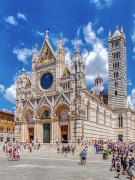 Visitors exploring the facade of Siena Cathedral, Italy.