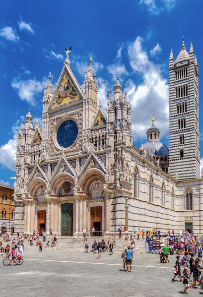 Visitors exploring the facade of Siena Cathedral, Italy.