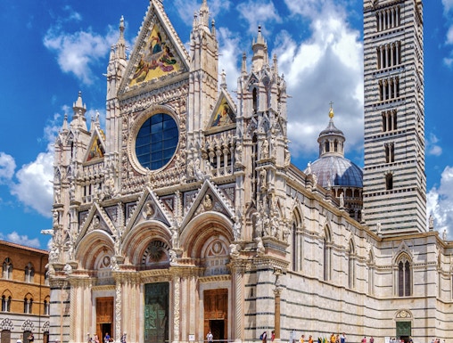 Visitors exploring the facade of Siena Cathedral, Italy.