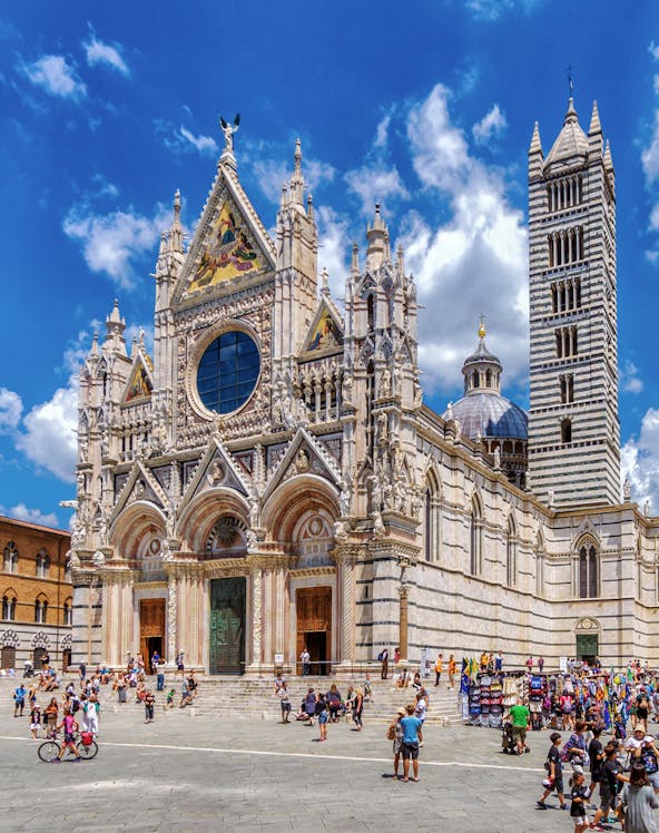 Visitors exploring the facade of Siena Cathedral, Italy.