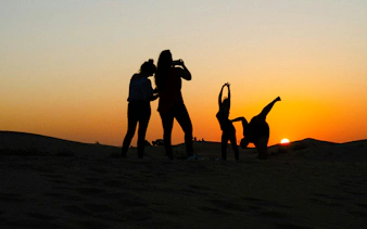 Silhouettes of people enjoying a sunset during a Dubai desert safari.