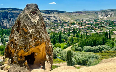 Rock formation with cave entrance overlooking Cappadocia landscape on Green Tour.