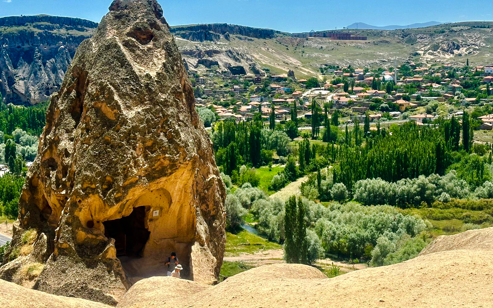 Rock formation with cave entrance overlooking Cappadocia landscape on Green Tour.