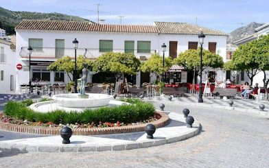 Fountain and café in Benalmádena Pueblo square, part of self-guided city exploration game.