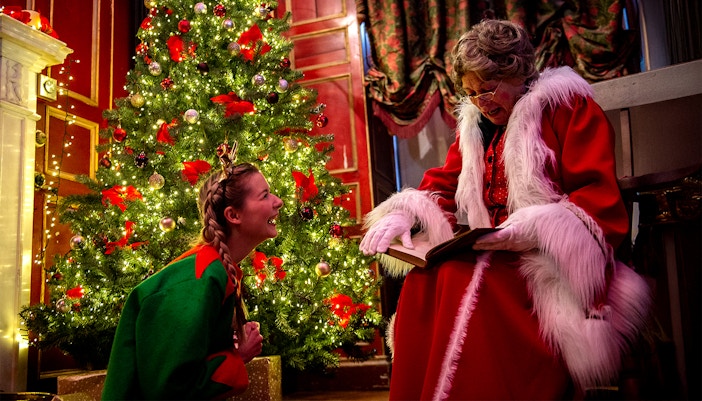 Santa reading to a child by a decorated Christmas tree at Warwick Castle.