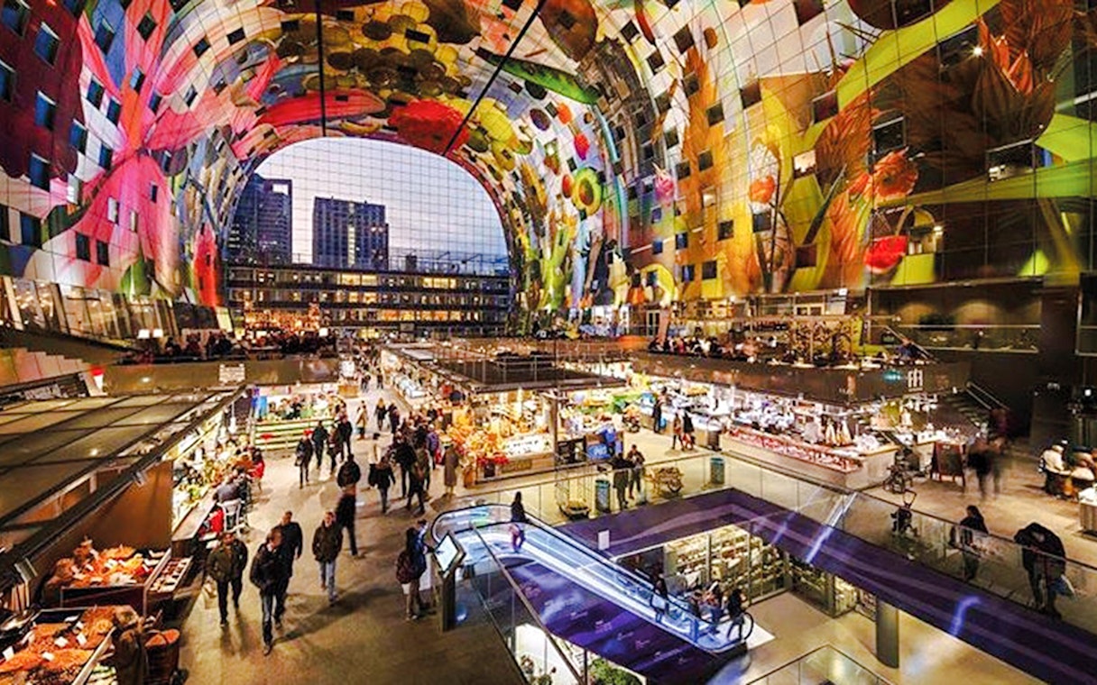 Interior view of Market Hall in Rotterdam with vibrant ceiling art and bustling food stalls.