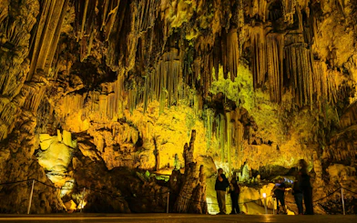 Visitors exploring illuminated stalactites in the Caves of Nerja, Spain.