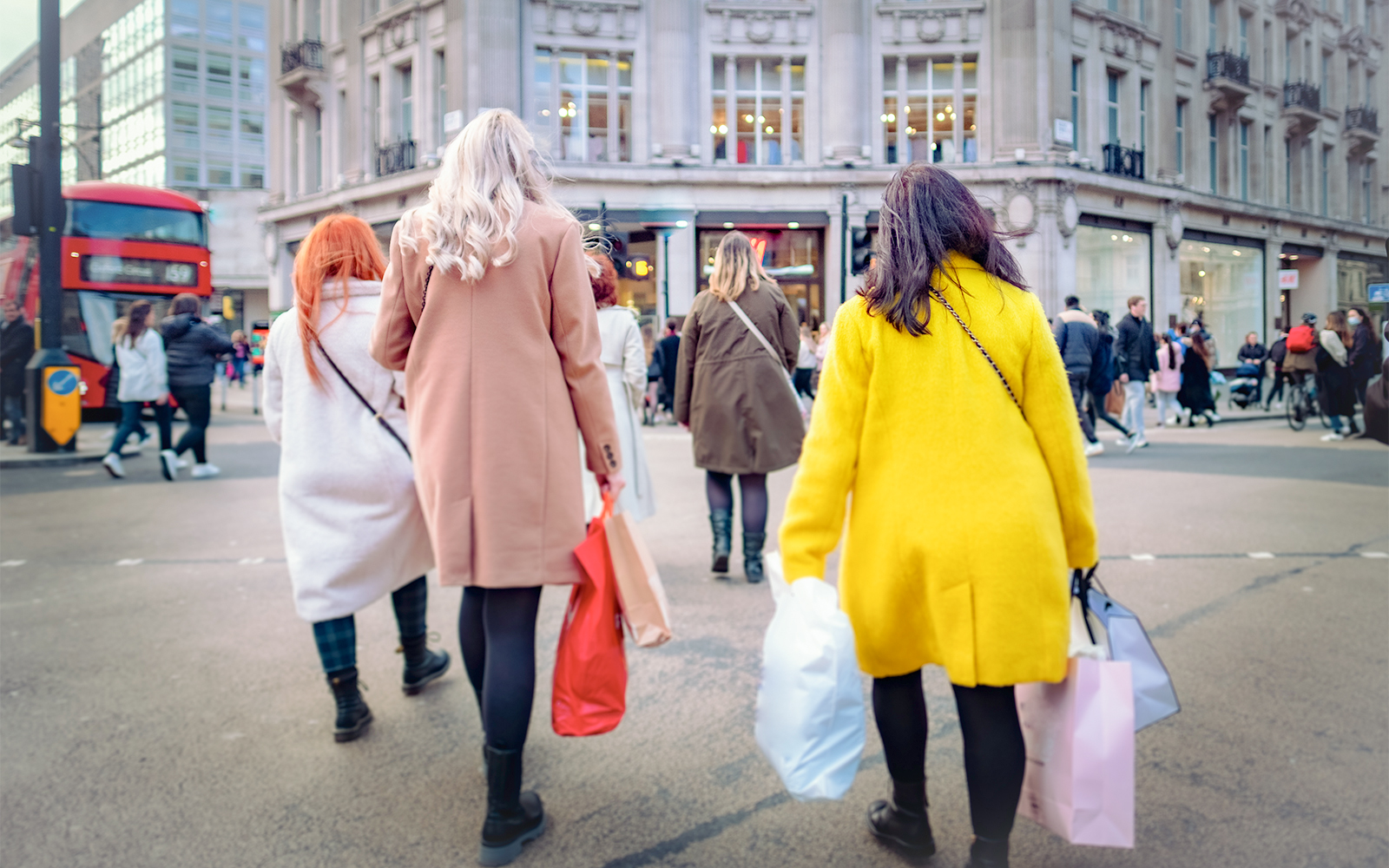 Shoppers walking at Oxford Circus in London with shopping bags.