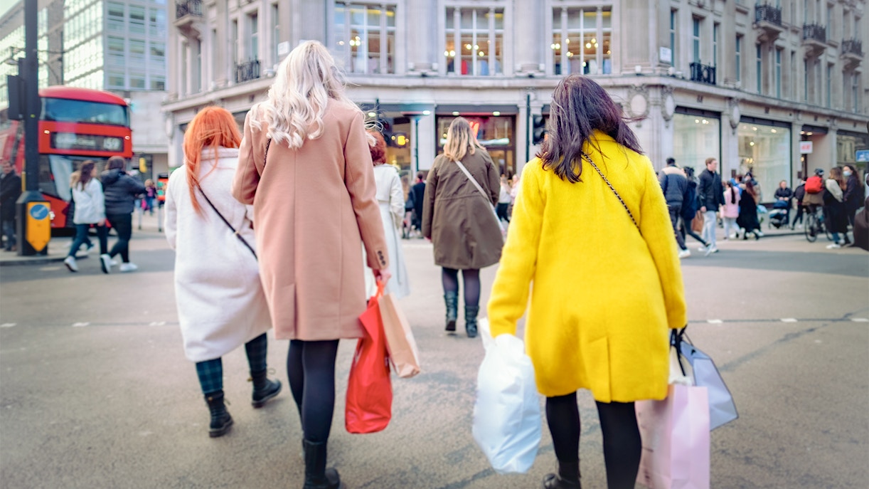 Shoppers walking at Oxford Circus in London with shopping bags.