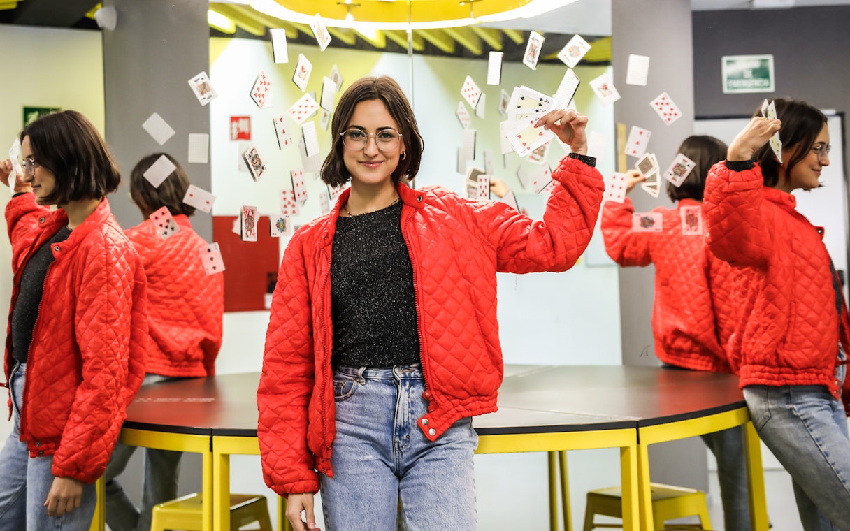 Person holding playing cards in front of mirrors at the Museum of Illusions.