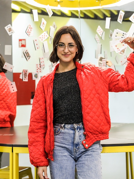 Person holding playing cards in front of mirrors at the Museum of Illusions.
