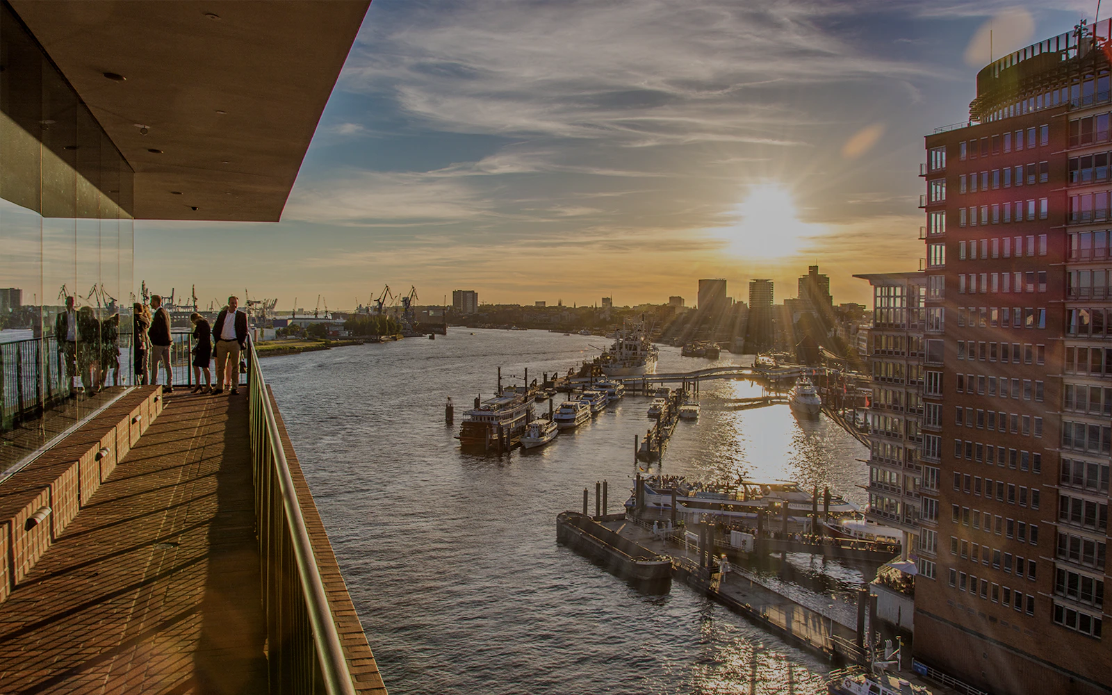 Visitors on Elphi Plaza balcony overlooking HafenCity harbor at sunset, Hamburg.