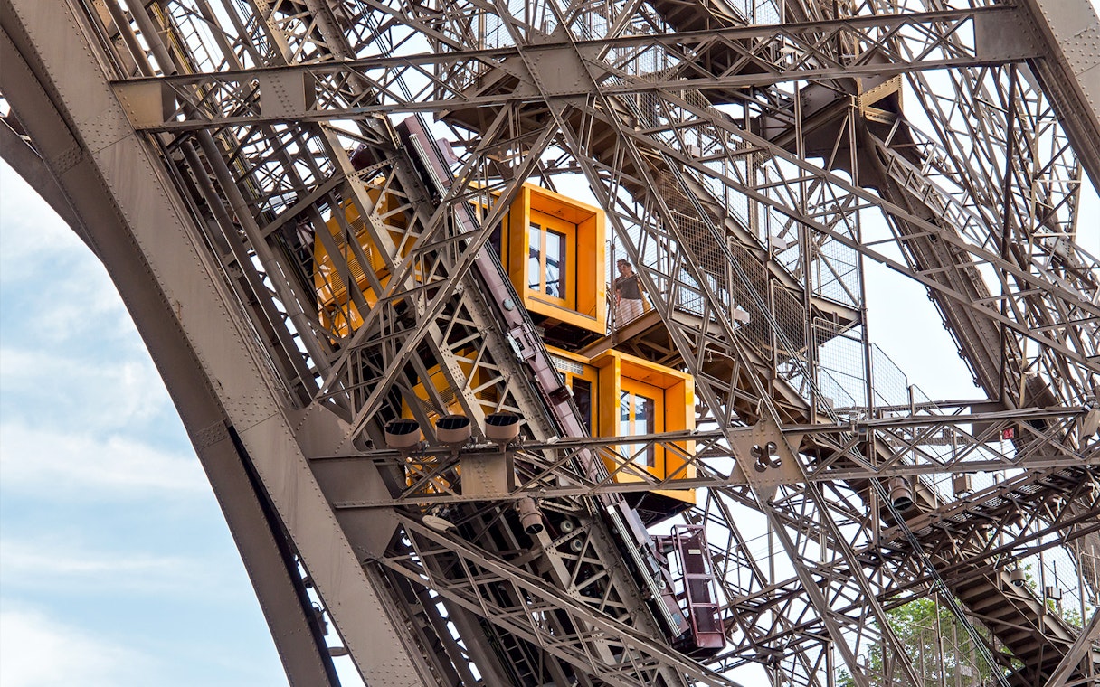 Eiffel Tower elevator ascending with visible structural details, Paris in a Day Guided Tour.