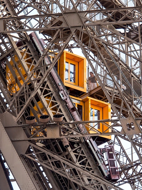 Eiffel Tower elevator ascending with visible structural details, Paris in a Day Guided Tour.