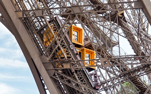 Eiffel Tower elevator ascending with visible structural details, Paris in a Day Guided Tour.