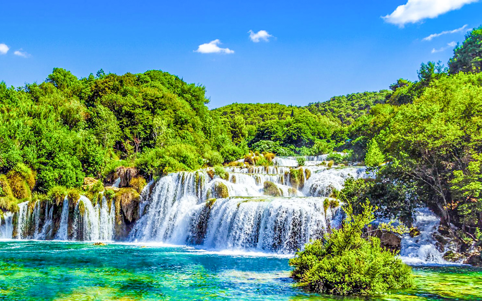 Krka Waterfalls cascading over rocks surrounded by lush greenery in Croatia.