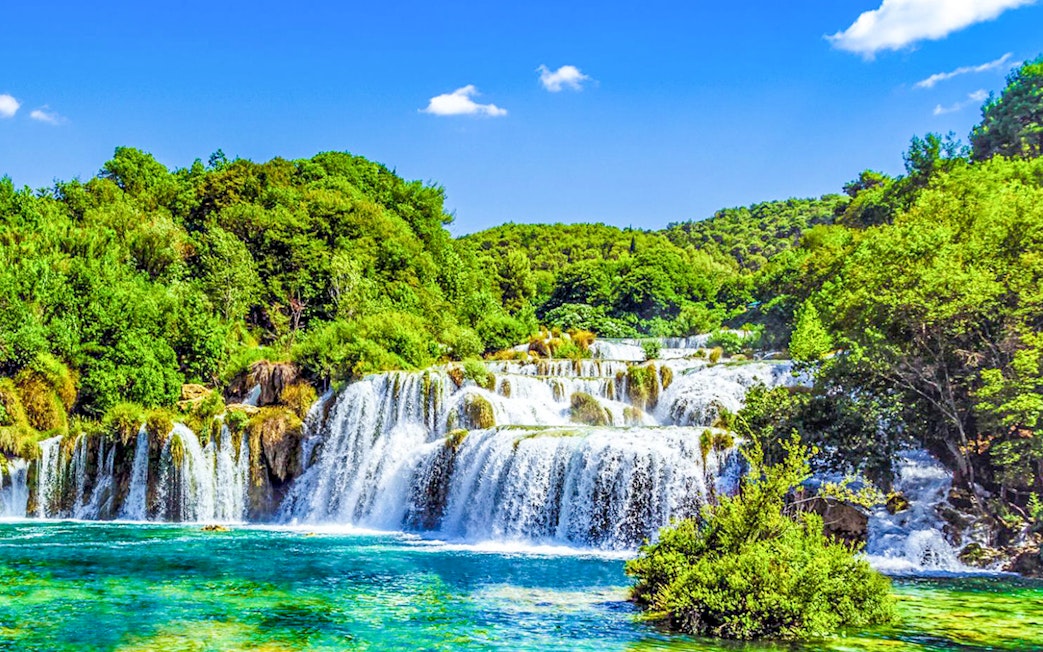 Krka Waterfalls cascading over rocks surrounded by lush greenery in Croatia.