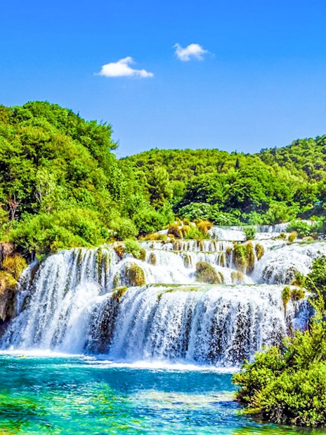 Krka Waterfalls cascading over rocks surrounded by lush greenery in Croatia.