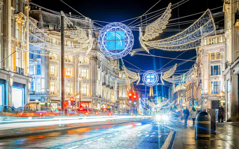 London street adorned with Christmas lights and decorations during Santa's Magical Express bus tour.