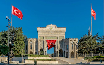 Main entrance gate of Istanbul University in Beyazıt Square, Istanbul, with Turkish flags.