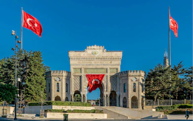 Main entrance gate of Istanbul University in Beyazıt Square, Istanbul, with Turkish flags.