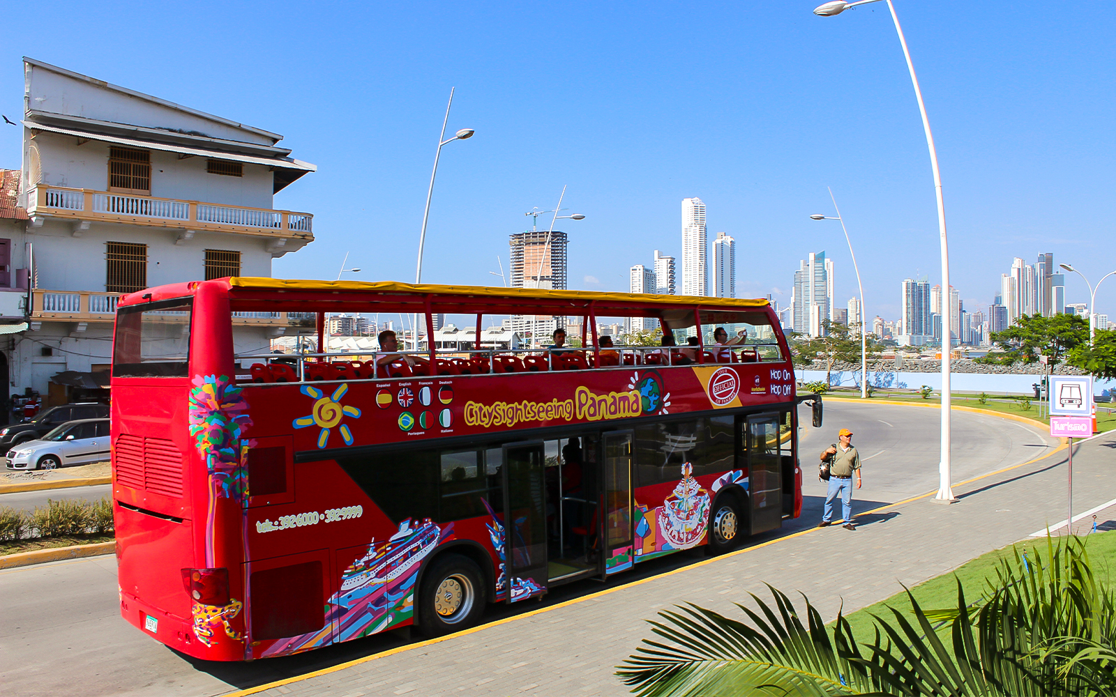 Red double-decker bus on Hop On Hop Off tour in Panama City with skyline in background.