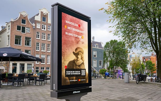 Outdoor sign promoting Rembrandt House tour in Amsterdam city square.