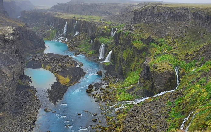 Waterfalls cascading into a turquoise river in Landmannalaugar Highlands, Iceland.