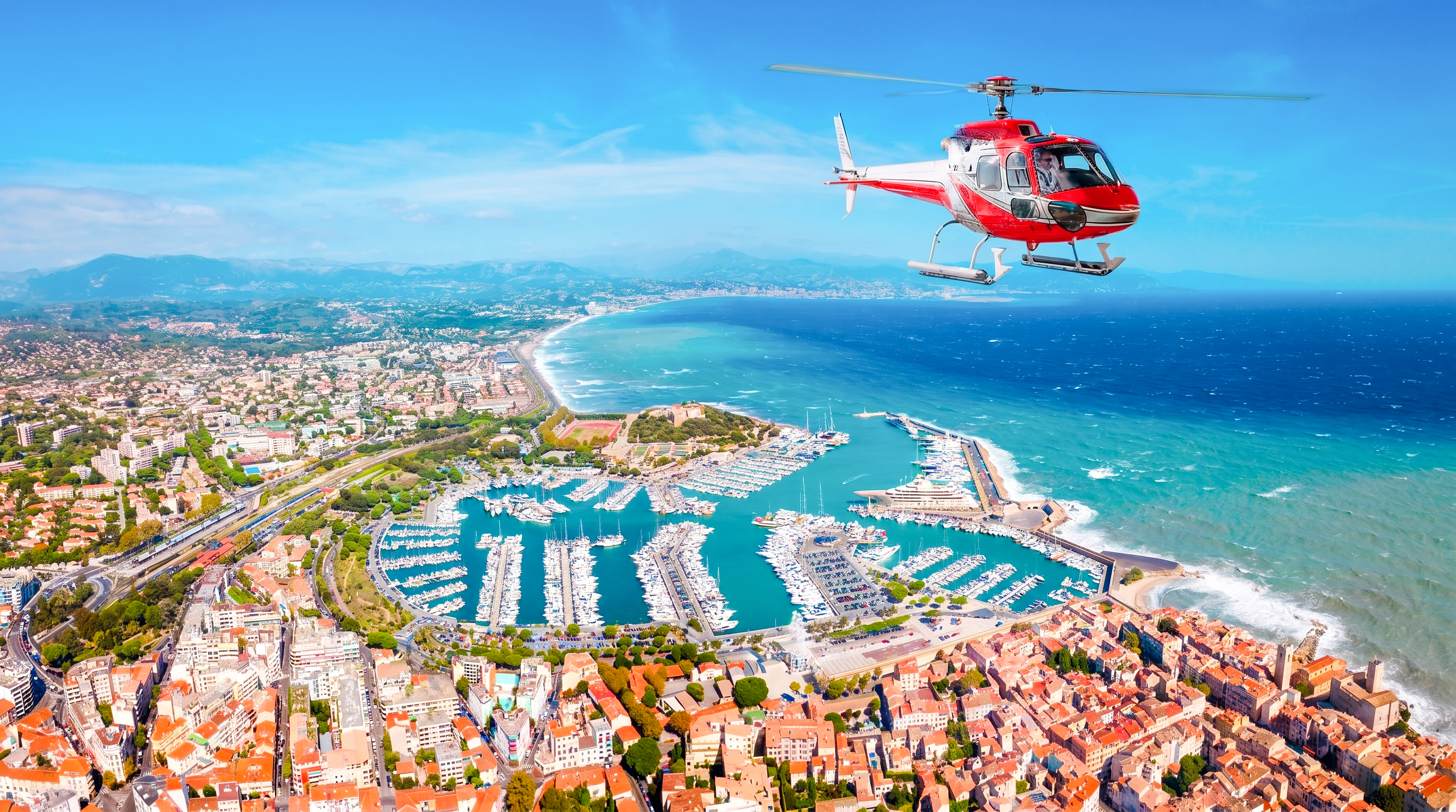 Helicopter flying over Nice coastline and marina during panoramic tour.