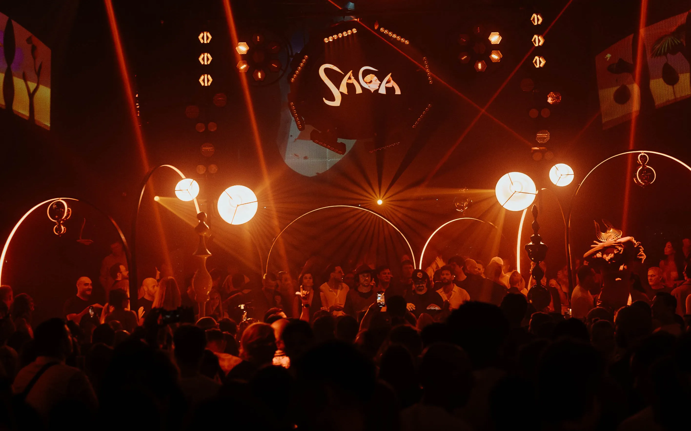 DJ performing at Club Chinois during SAGA event, Ibiza, with vibrant lights and crowd.