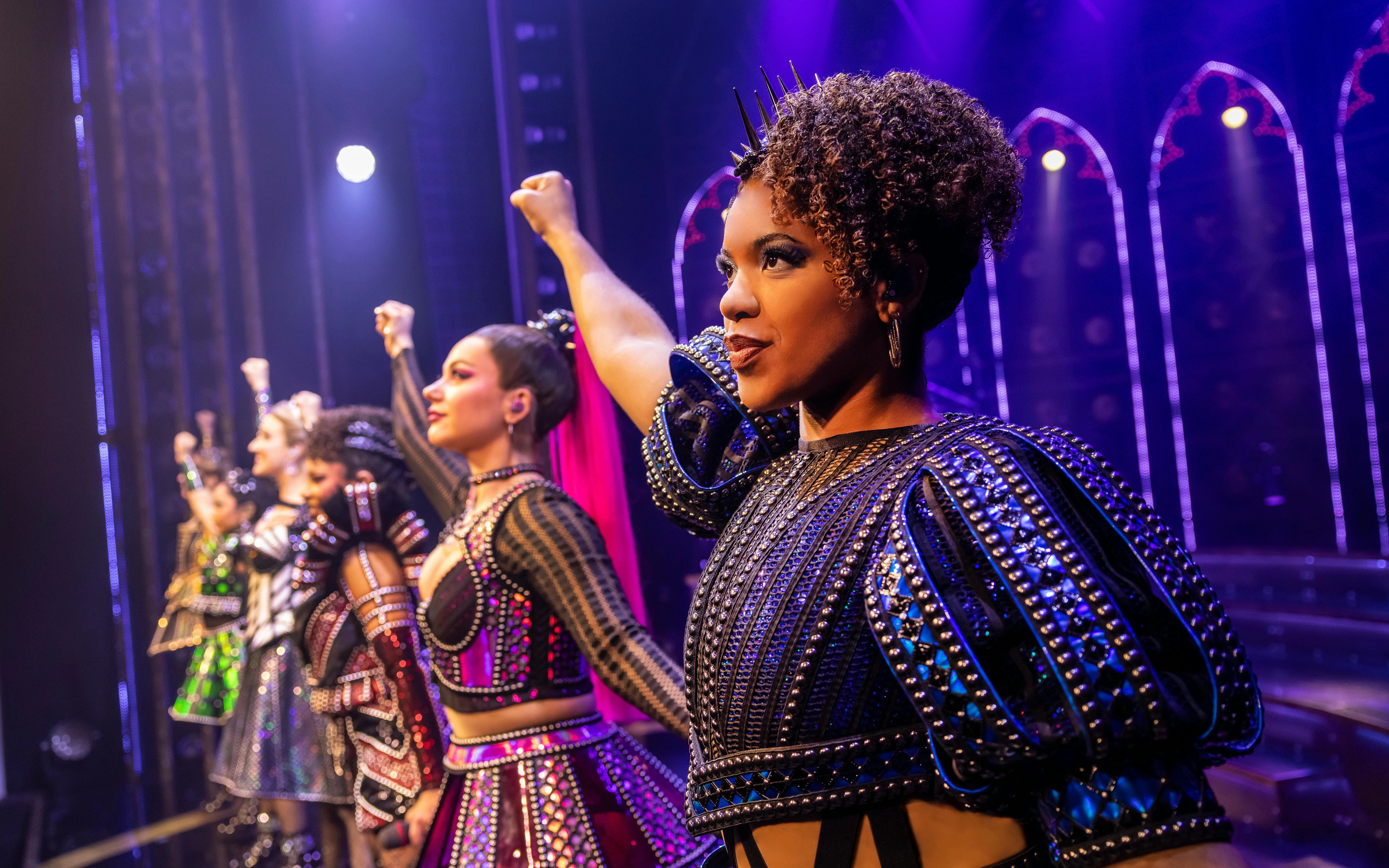 Performers in vibrant costumes on stage during Six musical, West End.