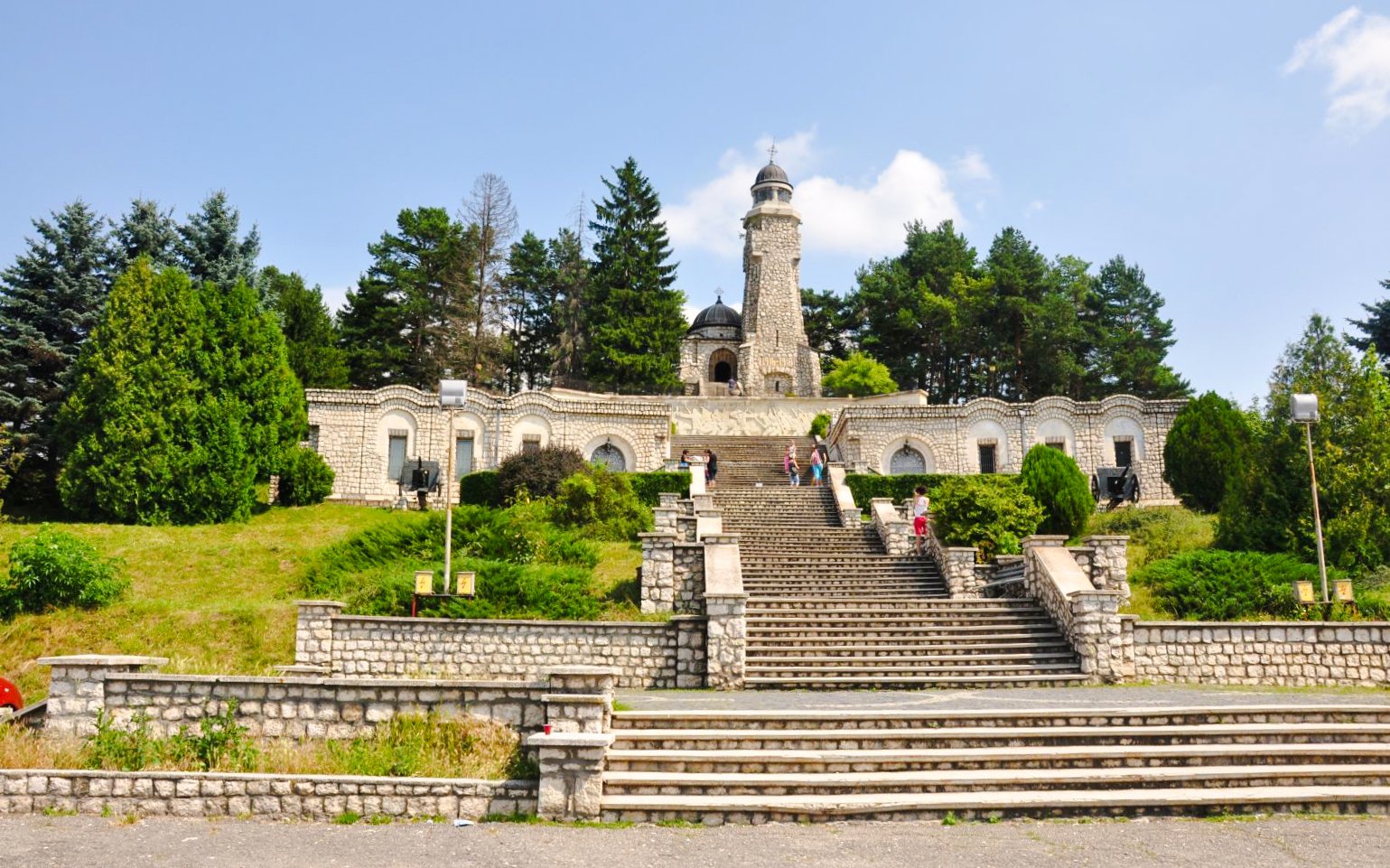 Heroes Mausoleum in Romania with stone steps leading to the monument surrounded by trees.
