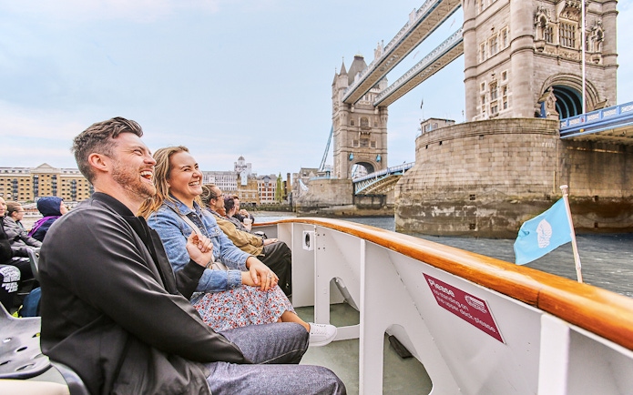 Tourists enjoying a cruise with a view of the Tower Bridge in London.