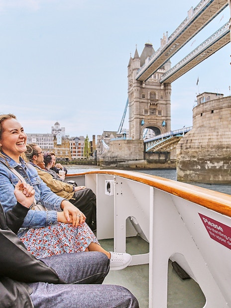 Tourists enjoying a cruise with a view of the Tower Bridge in London.